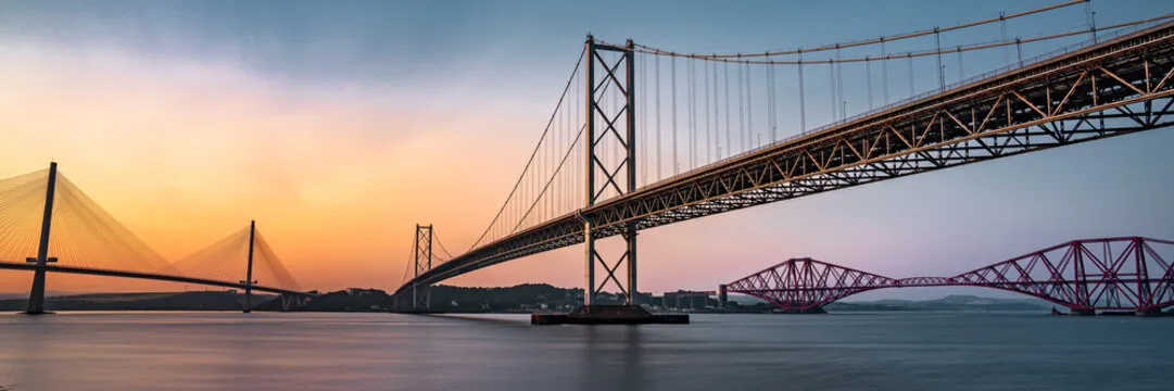 The three Forth bridges at sunset — Queensferry Crossing, Forth Road Bridge, and Forth Bridge spanning the Firth of Forth